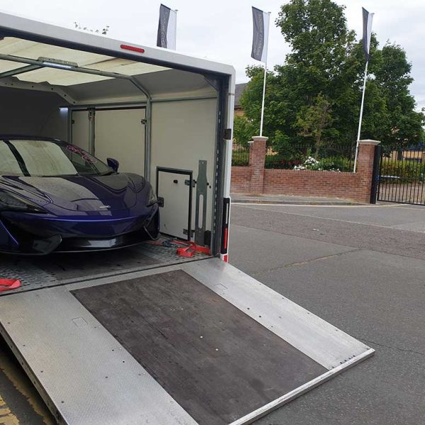 Enclosed car trailer parked beside a residential entrance
