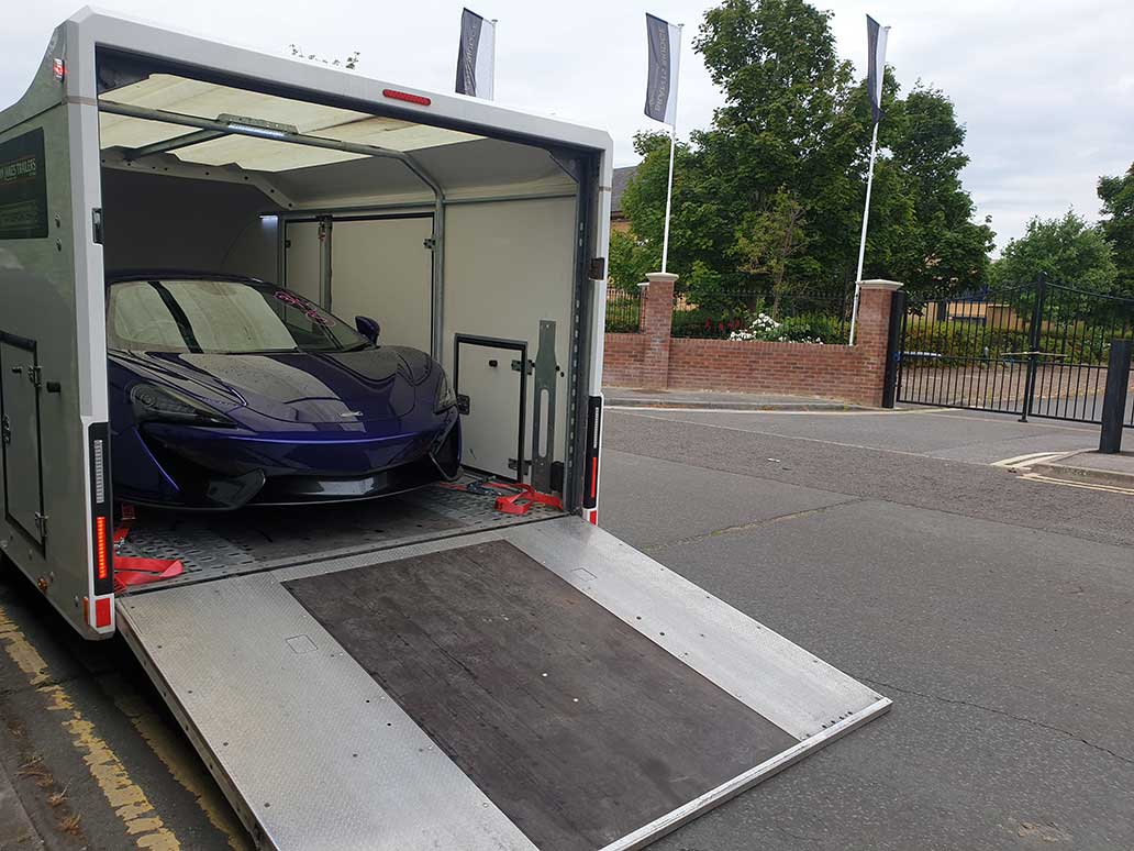 Enclosed car trailer parked beside a residential entrance