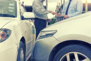 Vehicle keys being handed over beside a car