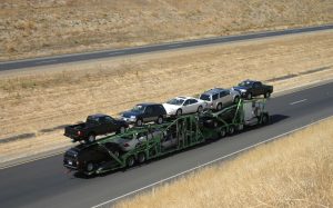 Open car carrier transporting vehicles along a highway
