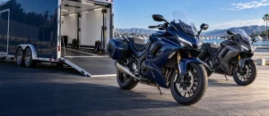 Modern navy and graphite motorcycles beside an open enclosed transport trailer