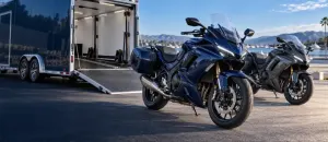 Modern navy and graphite motorcycles beside an open enclosed transport trailer
